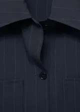 Camisa azul marino a rayas diplomáticas, de corte recto, con cuello camisero, cierre frontal con botones y dos bolsillos de parche en la parte delantera.