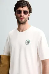 Camiseta blanca de corte holgado, cuello redondo y mangas cortas. Presenta un bordado y estampado combinado en el frente.