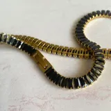 Collar choker elegante de acero hipoalergénico enchapado en oro, con incrustaciones de circonia y diseño en color negro.