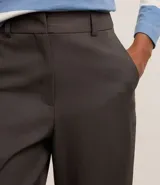 Pantalón de vestir gris claro, de corte recto, con bolsillos laterales y traseros. Se ajusta a la cintura con cinturón de cuero negro.