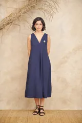 Vestido midi azul con textura crepé, escote en V, sin mangas, bolsillos laterales y aplique de flor con piedras facetadas en el escote.