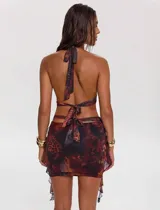 Vestido corto con estampado abstracto en tonos marrones y negros, escote halter con detalle de aro metálico y falda con drapeado lateral.