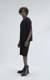 Remera negra de tejido de punto con moldería oversize, confeccionada en viscosa y poliéster. Presenta un diseño de malla con pequeños agujeros y un dobladillo acanalado.