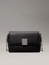 Cartera cruzada negra de piel sintética granulada, con correa de cadena plateada y cierre de solapa con placa metálica con el logo de Calvin Klein grabado.