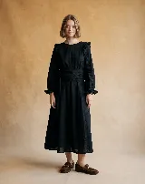 Vestido midi negro de algodón con textura de lunares en relieve, escote redondo, mangas largas con volados en los hombros y puños elásticos con volados.