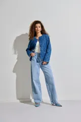 Campera de denim azul con diseño acolchado, cuello redondo, cierre con botones y bolsillos laterales.