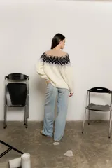 Sweater de punto color crudo con diseño geométrico en negro, gris y beige en la parte superior.
