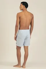 Short de baño celeste con rayas verticales blancas y logo bordado en negro en la pierna derecha.