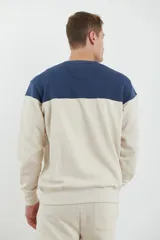 Sweater deportivo color beige con corte colorblock azul marino en el pecho y puños elastizados.