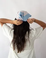 Pañuelo cuadrado de seda color celeste con borde azul y estampado de cerezas, frutillas, lazos y copas de martini.