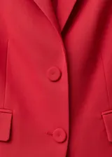 Blazer rojo con solapas de muesca, cierre frontal con dos botones y bolsillos delanteros con solapa.