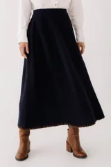 Falda midi tejida color azul marino, de corte acampanado y cintura alta. Presenta detalle de pespunte marrón en el ruedo.