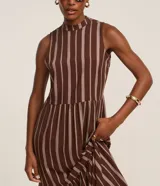 Vestido midi evasé sin mangas, confeccionado en viscosa, con cuello alto, corte en la cintura, recortes fruncidos en la pollera y rayas verticales desencontradas.