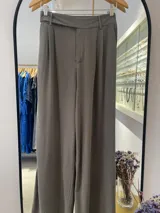 Pantalón de vestir de tiro alto, color verde seco, con pliegues marcados en la parte delantera y un cinturón incorporado del mismo tejido. El corte es ancho y fluido.