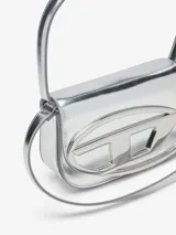 Bolso bandolera Diesel modelo 1DR, color violeta metalizado, con asa corta rígida y correa larga extraíble. Presenta solapa con cierre magnético y logo ovalado "D" en relieve.