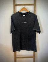 Remera negra con efecto gastado, corte amplio y estampado de montañas con la palabra 'Mountain' en blanco.