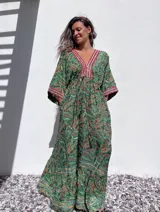 Vestido túnica largo con estampado paisley en tonos verdes, amarillos y rojos. Presenta escote en V con bordado decorativo y mangas 3/4 amplias.