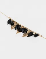 Collar corto dorado con cadena de eslabones y extensión, con dijes colgantes de resina negra y metal dorado.
