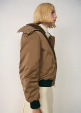 Campera bomber color marrón con interior de borreguito, cuello redondo, cierre frontal con cremallera, puños elásticos y dos bolsillos laterales.