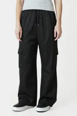 Pantalón negro de corte ancho con cintura elastizada y cordón ajustable. Presenta una franja vertical blanca a lo largo de la pierna y un bolsillo tipo cargo en el muslo.