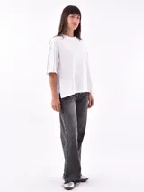 Remera blanca de corte holgado con mangas cortas y detalle de rayas verticales negras en mangas y laterales.