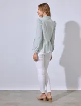 Camisa estampada a rayas verticales en tonos verde y blanco, con cuello con solapa, abertura central con botones y terminación en volado.