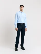 Traje de vestir azul marino con camisa celeste, cinturón de cuero negro y zapatos de vestir negros.