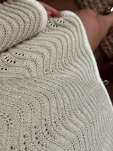 Vestido corto tejido en algodón y lurex color crudo, con punto pavo real, manga larga y escote en la espalda.