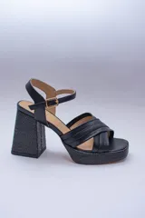 Sandalias negras de plataforma con taco cuadrado y tiras cruzadas en el empeine. Cuenta con pulsera al tobillo con hebilla dorada.