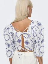 Top corto blanco con estampado de flores azules, cuello cuadrado y mangas cortas abullonadas.
