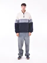 Buzo de polar con cierre parcial y cuello alto, con diseño a bloques de color: blanco, gris y azul marino.
