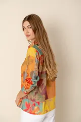 Camisa de manga larga con cuello clásico y botones frontales. Presenta un estampado floral multicolor en tonos amarillo, naranja, celeste y rojo.