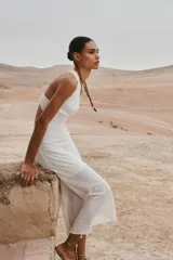 Vestido midi blanco con bordados florales perforados, escote en V, sin mangas y tirantes cruzados en la espalda.