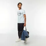 Camiseta celeste de manga corta con cuello redondo. Estampado frontal con el texto "East Hampton New York - United States" y un dibujo de un yate.