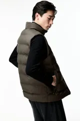 Chaleco puffer color verde oliva, con cuello alto y cierre frontal. Cuenta con bolsillos laterales con cierre y un bolsillo interno con botón a presión.
