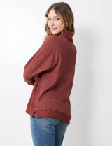 Polera de punto color marrón con detalles en botones en el cuello y corte holgado.