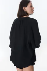 Camisa beige de manga larga con botones y detalles de encaje.