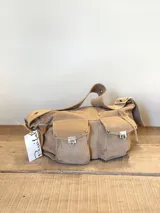 Bolso bandolera de gamuza color óxido, con correa ajustable y múltiples bolsillos frontales con cierre metálico.