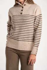 Sweater de lana y nylon, color beige jaspeado con rayas horizontales marrones oscuras. Presenta cuello alto con abertura frontal abotonada con tres botones marrones.