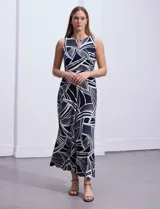 Vestido largo de seda fría con estampado abstracto en blanco y azul marino. Tiene cuello a la base cruzado con abertura ojal y aplique metálico.