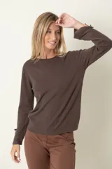 Buzo color beige de punto, con cuello redondo y puños abiertos decorados con moña y perla.