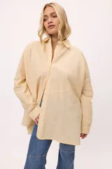 Camisa oversize a rayas verticales color amarillo y blanco, con cuello camisero, manga larga y cierre frontal con botones.