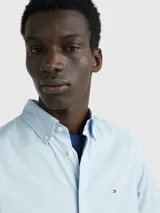 Camisa celeste de mangas cortas, confeccionada en popelín de puro algodón. Tiene cuello abotonado, bajo redondeado y logo de Tommy Hilfiger bordado en el pecho.
