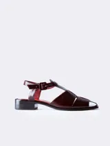 Sandalias de cuero color borgoña con textura croco, diseño cerrado en la parte delantera con aberturas laterales, punta cuadrada y cierre con hebilla ajustable en el tobillo. Taco ancho de 3 cm.