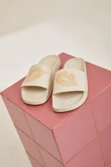 Sandalias tipo slides color crema con estampado de besos en color dorado.