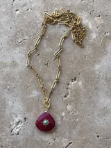 Cadena dorada con eslabones rectangulares y dije en forma de gota color borgoña con detalle de estrella turquesa en el centro.