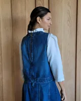 Chaleco blanco con cuello redondo y sisas amplias. Presenta costuras verticales a la vista y un bolsillo lateral con detalle de costura en forma de equis.