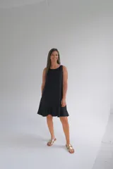 Vestido midi negro sin mangas, con escote redondo y volado en el ruedo.