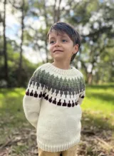 Sweater tejido a mano en lana merino color crudo, con diseño de guarda pampa en tonos verde, marrón y bordó en la parte superior.