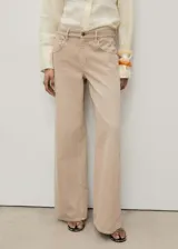 Pantalón de jean color beige, de corte wide leg, tiro bajo, con cinco bolsillos y cierre frontal con cremallera y botón.